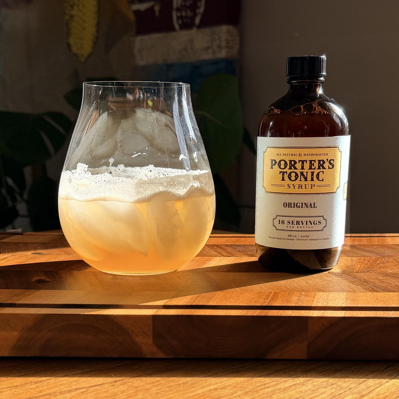 A Porter’s Tonic gin and tonic over ice beside a bottle of Porter’s Tonic Original on a wood board